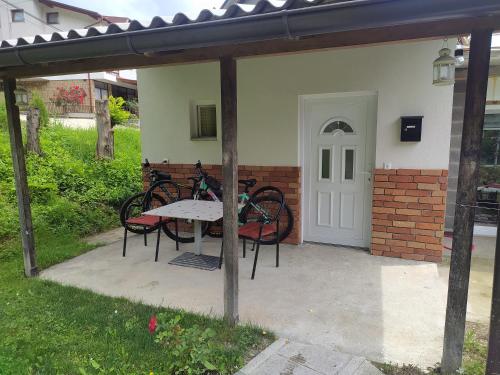 patio con mesa, sillas y puerta blanca en Lenilenii Bungalow, en Jajce