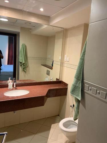 a bathroom with a sink and a toilet and a mirror at Sahara private apartment in Dubai