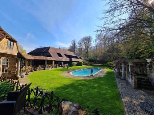 a backyard with a swimming pool and a house at Powdermills Country House Hotel in Battle