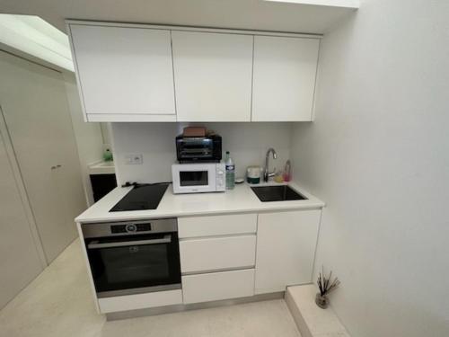 una pequeña cocina con armarios blancos y microondas en Studio port hercule Monaco en Montecarlo