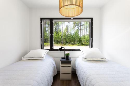 2 bedden in een witte kamer met een raam bij Villa Eslahti - Seafront/Jacuzzi in Porvoo