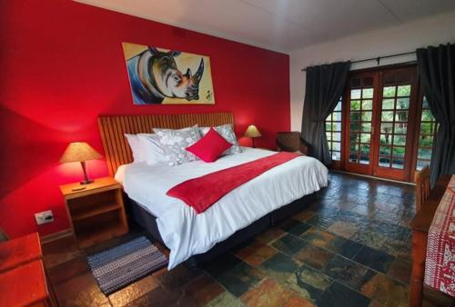 1 dormitorio rojo con 1 cama con pared roja en Paradise View Guesthouse, en Graskop