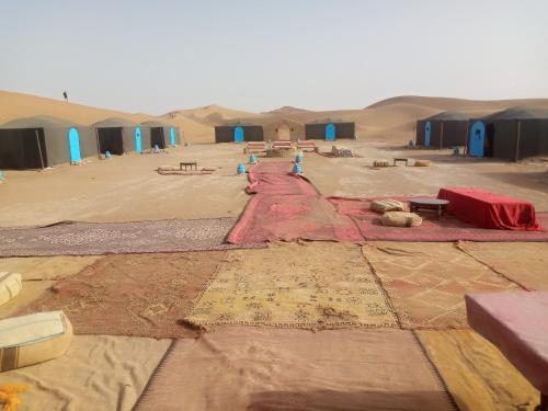 a desert with a group of huts in the sand at M'hamid Adventures in Mhamid