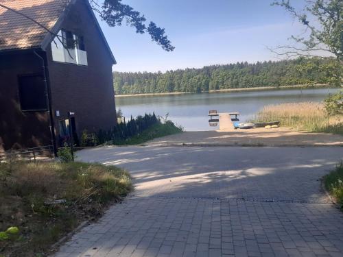 a building with a bench next to a lake at Apartament nr 9 Mazurskie Klimaty in Tomaszkowo