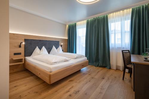 a bedroom with a large bed with green curtains at Design Hotel Frauenschuh in Salzburg