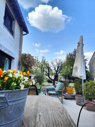 un patio con una mesa con flores y una sombrilla en La parenthèse rémoise, 