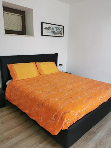 a bed with an orange comforter in a bedroom at La casa de Nani in Porcen