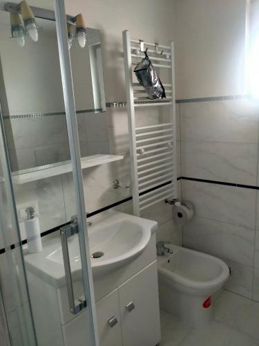 a white bathroom with a sink and a toilet at Maramureș plai cu flori in Ocna Şugatag