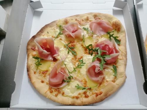 une pizza au jambon et au fromage dans une boîte dans l'établissement L escale de larcher, à Saint-Aubin-de-Nabirat