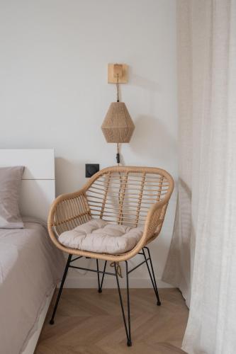 une chaise en rotin dans une chambre à côté d'un lit dans l'établissement Appartement 2 pièces Montpellier centre, à Montpellier