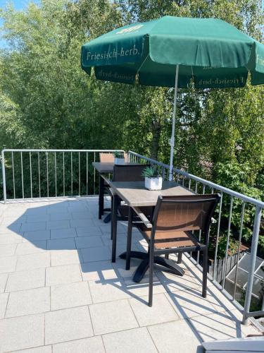 einen Tisch und Stühle unter einem Sonnenschirm auf einer Terrasse in der Unterkunft Deichblick-Carolienensiel in Carolinensiel
