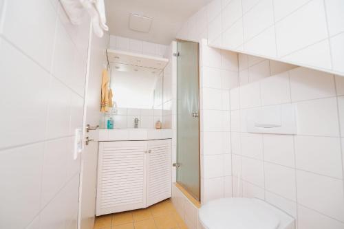 a white bathroom with a toilet and a sink at Ferienwohnung Menzer am See in Öhningen