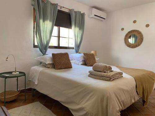 a bedroom with a large white bed with towels on it at Casa Lavadeira - VINHAS de NEXE in Faro