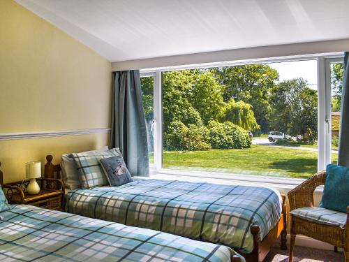 a bedroom with two beds and a large window at Beachborough Park Summer House in Postling