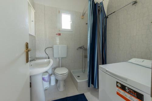 a bathroom with a sink and a toilet and a shower at Spacious seaside house in Nea Potidaea