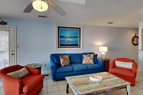 a living room with a blue couch and two red chairs at Sea Oats Gulf Shores #C206 in Gulf Shores