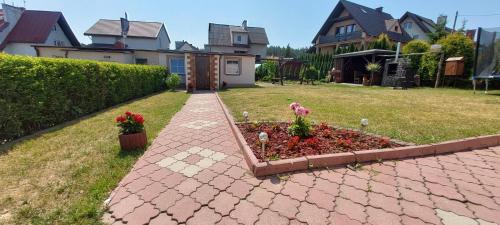 a brick walkway in a yard with a flower garden at Domek Tomek in Wilkasy