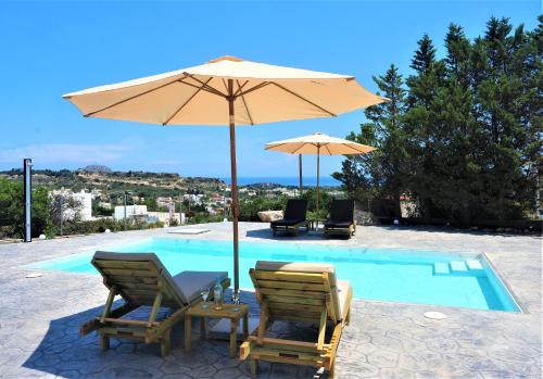 - deux chaises et un parasol à côté de la piscine dans l'établissement Villa Aurora Dome, à Afantou
