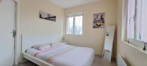 a white bedroom with a bed and a window at Appartement 3 étoiles de 63m2 in Cabourg