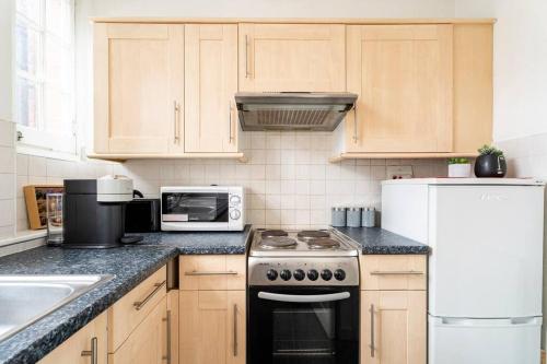 eine Küche mit einem Herd und einer Mikrowelle in der Unterkunft Cozy Apt in Central London in London