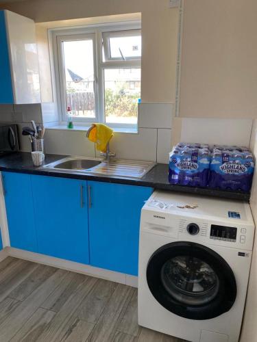 a kitchen with blue cabinets and a washing machine at A home away from home in Dagenham