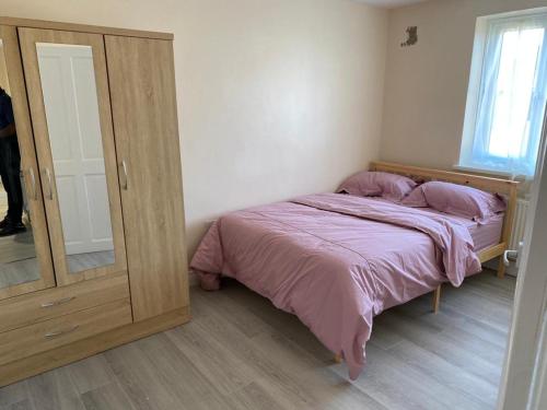 a small bedroom with a bed and a mirror at A home away from home in Dagenham