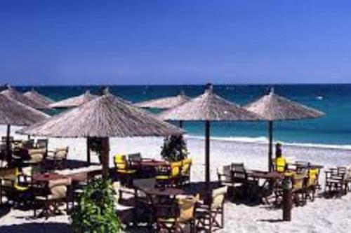 a beach with many tables and chairs and umbrellas at Konstantinos Apartmend Chalkidiki in Sozopoli