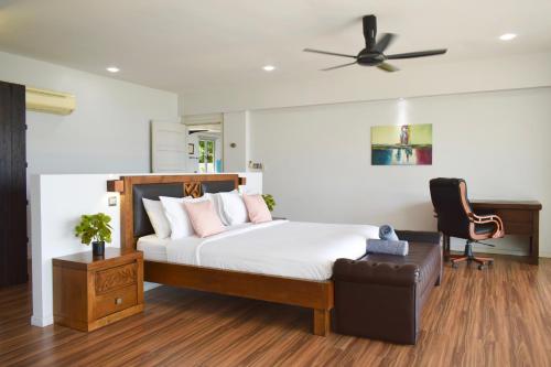 Aroha Seaview Villa - Private Pool - في بانتايْ سينانج: غرفة نوم بسرير وكرسي ومروحة سقف