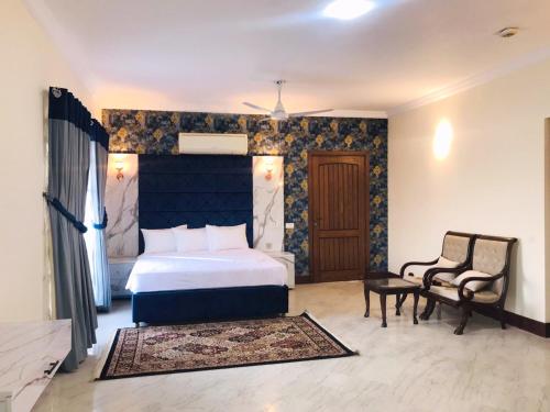 a bedroom with a king sized bed and a chair at Royal Palace Boutique Hotel in Islamabad