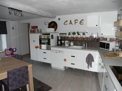 une cuisine avec des armoires blanches et une table à l'intérieur dans l'établissement Maison au calme, à Eyravazet