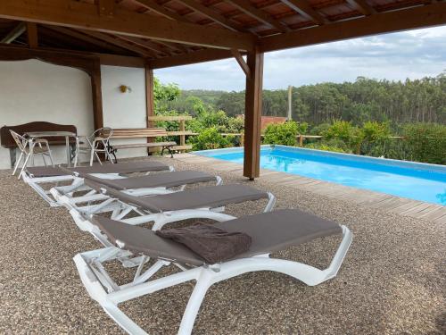 a group of lounge chairs next to a swimming pool at Casa das Andorinhas - Campo e Piscina in Bajouca de Cima