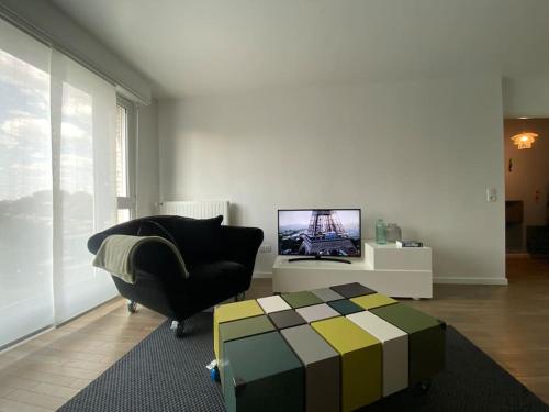uma sala de estar com uma cadeira e uma televisão em Appartement proche Paris & Orly em Chevilly-Larue