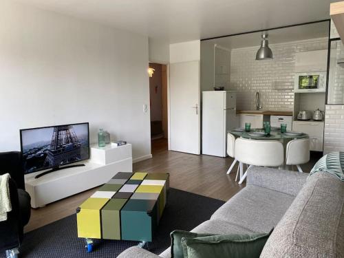 a living room with a couch and a tv and a kitchen at Appartement proche Paris & Orly in Chevilly-Larue