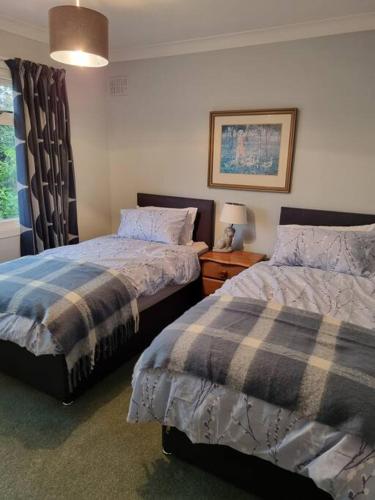 a bedroom with two beds next to a window at Shunters Cottage in Darnick