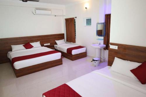 una camera d'albergo con due letti e una televisione di CHANDRODAYAM RESIDENCY a Karaikal