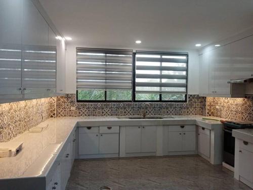 uma cozinha com armários brancos, um lavatório e duas janelas em Taylors Country Home by Travellers Inn at The Ground em Tangaro