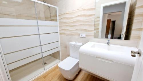 Un baño con inodoro, lavabo y ducha. en Villa Candari, en Chiclana de la Frontera