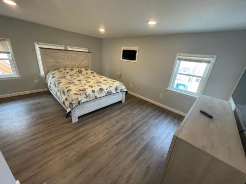 a bedroom with a bed and wooden floors and windows at Dupont Beach House C in Seaside Heights