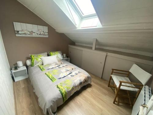 une chambre mansardée avec un lit et une fenêtre dans l'établissement Appartement relaxant au bassin, à La Teste-de-Buch