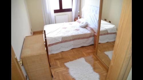 ein kleines Schlafzimmer mit einem Bett und einem Spiegel in der Unterkunft El Descanso in Oviedo