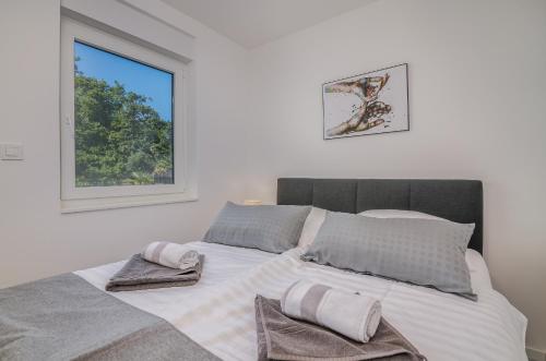 a white bedroom with a large bed with towels on it at Apartment Manuela in Njivice