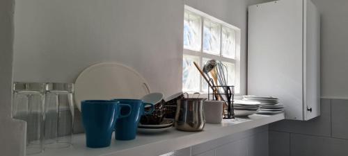 a kitchen counter with cups and plates and a window at Apartmani Centar Seline Paklenica in Seline
