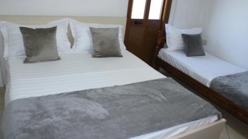 two beds in a room with white sheets and pillows at Deni's Family Apartment in New BLVD in Tirana