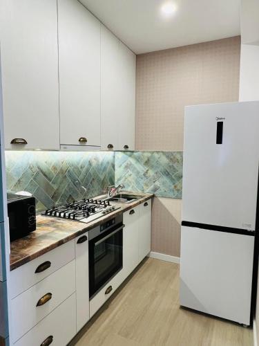 a kitchen with white cabinets and a white refrigerator at AURA in Kutaisi