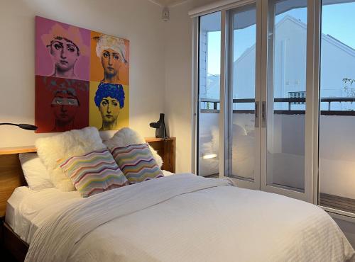 ein Schlafzimmer mit einem Bett mit einem großen Gemälde an der Wand in der Unterkunft Cosy Cottage 2 Bedroom Great Location Close to Transport in Sydney