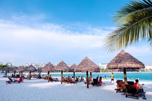 a group of people sitting on a beach with straw umbrellas at Apartment 1BR-FL27th-R103 Building-Vinhome Ocean Park in Hanoi