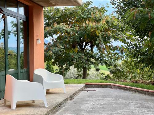 zwei weiße Stühle auf der Veranda eines Hauses in der Unterkunft Casa Mimose Rosa in SantʼAngelo in Pontano