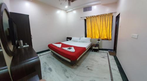 a bedroom with a bed with a red blanket and a window at Hotel Gujrat in Nagpur
