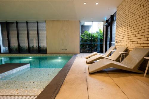 - une piscine avec des chaises et une table dans une maison dans l'établissement PoolGymconference Room Executive living Great Location, à Melbourne