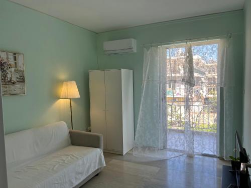 sala de estar con sofá blanco y ventana en Sun Beach Apartment en Anavissos
